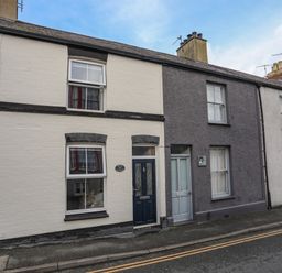 A street view of terraced houses with different colored facades and doors at Amelie Cottage in Beaumaris Anglesey