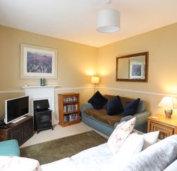 A living room with two sofas a television a bookshelf and lamps at Amelie Cottage Beaumaris Anglesey