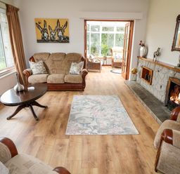 A living room with sofas a wooden coffee table a rug a fireplace and a painting of donkeys at Glebe Farm Cottage in Rathfriland County Down