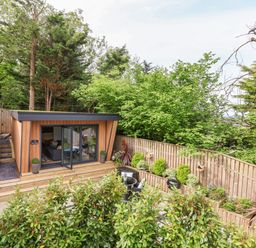 A small garden room with glass doors opening to a patio with outdoor seating and plants at The Nest in Prestatyn