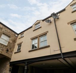 Exterior view of a building with multiple windows and satellite dishes attached to the wall at Lavenna in Alnwick