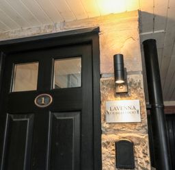 A black door with the number 1 next to a stone wall with a light fixture and a sign reading Lavenna 1 Jubilee Court at Lavenna in Alnwick
