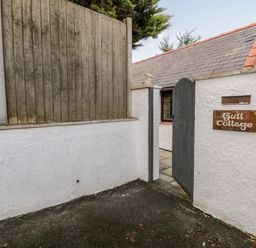 A white wall with a wooden gate and a sign reading Gull Cottage at Gull Cottage in Hermon near Newborough