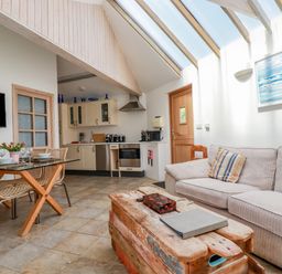 An open plan living area with a kitchen sofa wooden coffee table and dining table at Seashells Atlantic Highway near Bude