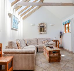 A living room with a beige sectional sofa wooden coffee table and chair under a skylight at Seashells Atlantic Highway near Bude