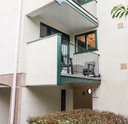 A balcony with two chairs and a small table outside a building with a light on and numbered signs at Bluebell Hill in Bowness-On-Windermere