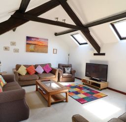 A living room with brown sofas a wooden coffee table a colorful rug and a television at The Corn Tallet in Westleigh near Bideford