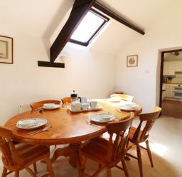 A dining room with a wooden table and six chairs set for breakfast at The Corn Tallet in Westleigh near Bideford