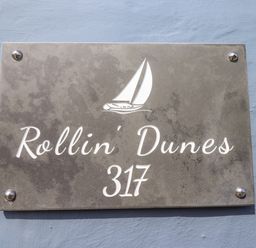 A house number sign with a sailboat graphic and the text Rollin Dunes 317 on a wall at Rollin Dunes in Humberston Lincolnshire