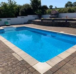 An outdoor swimming pool with stone steps and lounge chairs at Pen- y- Bryn @ Canllefaes in Penparc near Cardigan