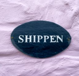 An oval black sign with white text reading SHIPPEN on a textured pink wall at The Shippen @ Canllefaes Penparc near Cardigan