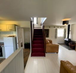 A living room with a staircase between kitchen and seating area at The Shippen @ Canllefaes in Penparc near Cardigan