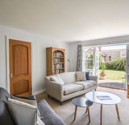 A living room with sofas a wooden door a bookcase a TV and glass doors leading to a garden at 12 The Gardens in Rousdon