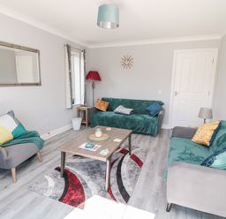 A living room with two green sofas one grey armchair and a wooden coffee table at 20 Southmead in Amble