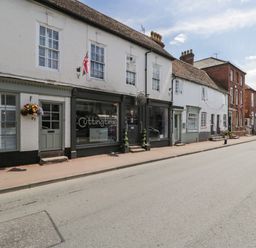 A street view of white and red brick buildings with shops and houses and a church spire in the background at Cuckoo Cottage in Upton Upon Severn