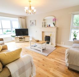 A living room with sofas, a coffee table, a television, a fireplace, and windows at 12 Hillview in Ludden near Buncrana