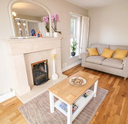 A living room with a beige sofa with yellow cushions a wooden coffee table and a beige fireplace at 12 Hillview Ludden near Buncrana