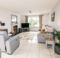 A living room with grey sofas a television a fireplace and a plant at 12 Hillview Ludden near Buncrana