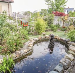 A garden with a pond surrounded by rocks and plants at Haddef Penmaenmawr in Penmaenmawr