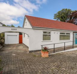 Exterior of a white building with a red tiled roof and a blue door with a driveway leading to a garage at Haddef Penmaenmawr in Penmaenmawr