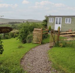 An outdoor view of a shepherds hut with a path and gate at The Journeyman Luxury Shepherds Hut in Barnoldswick