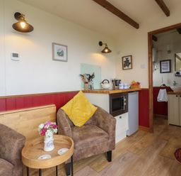 A living room with a sofa and kitchenette at The Journeyman Luxury Shepherds Hut in Barnoldswick