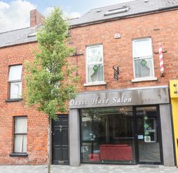 A brick building with a hair salon and a tree in front at The Upper Room in Ballymena