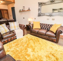 A living room with brown leather sofas yellow cushions and a yellow rug at The Upper Room in Ballymena