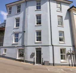 A blue building with white window frames and a black door on a street corner at Ferryside in Kingswear