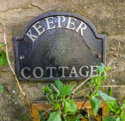 A sign reading Keeper Cottage on a stone wall with green leaves in front at Keepers in Nenthead near Alston