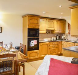 A kitchen with wooden cabinets and a dining table set with breakfast items at Chestnut in Nenthall near Alston