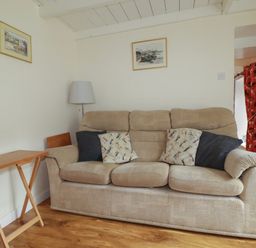 A living room with a sofa and a side table at Vi’s Valley View Pentewan