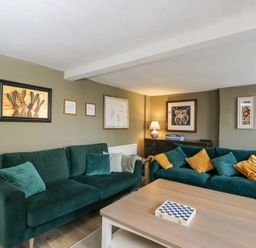 A living room with green sofas and a wooden coffee table with a chessboard at The Old School House in Lower Swell near Stow-On-The-Wold