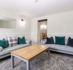 A living room with two sofas a wooden coffee table and a wall mirror at Somerset House in Othery near Middlezoy