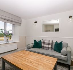 A living room with a gray sofa and a wooden coffee table by a window with flowers at Somerset House Othery near Middlezoy