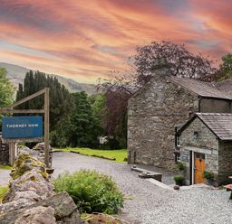 An outdoor stone building with a wooden door and a picnic table outside at Thorney How in Grasmere