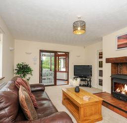 A living room with a leather couch wooden coffee table TV and fireplace at Spring Lodge in Eastcott near Kilkhampton
