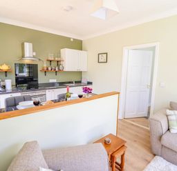 A kitchen and living area with a countertop set for two with wine glasses and a bottle at Cam O'r Fechan Annexe in Llangollen