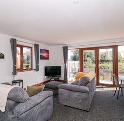 A living room with a television and a sofa at Delphine Lodge, Meadow View Lodges Brean