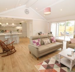 An open living room and kitchen with sofas and rocking chair at Y Beudy in Dinas near Bontnewydd