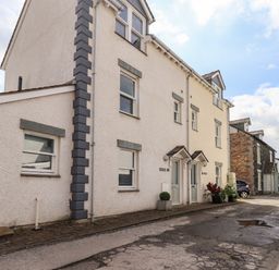 A street view of a row of white houses with multiple windows and doors with small awnings at Fell Sweep in Keswick