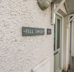 A house entrance with a green door and a sign reading Fell Sweep number 14 in Keswick