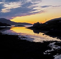 A sunset over a coastal inlet with houses and hills at Braemore Chalet Tarbert Isle Of Harris