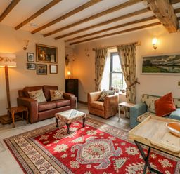 A sitting room with sofas armchairs a patterned rug and wooden beams at Pen Bont Home Farm in Upper Chapel near Builth Wells