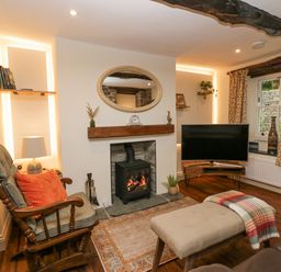 A living room with a rocking chair a TV and a fireplace at Style Cottage in Keswick