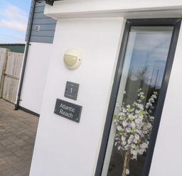 Exterior corner of a white building with a window showing flowers inside a glass vase at Atlantic Reach Marazion