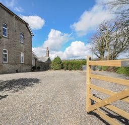 Gravel driveway with wooden gate and stone house under blue sky at Skylarks in No Mans Land near Looe