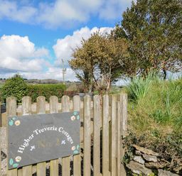 A wooden gate with a sign reading Higher Treveria Cottages No 2 and surrounding trees and greenery at Skylarks in No Mans Land near Looe