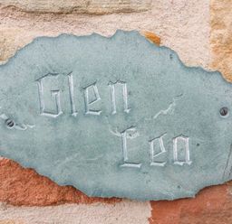 A carved stone plaque with the text Glen Lea attached to a brick wall at Glen Lea Giggleswick Settle