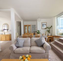 A living room with sofas a dining table with chairs and plants near large windows at Apartment at Morningside Hotel in Torquay